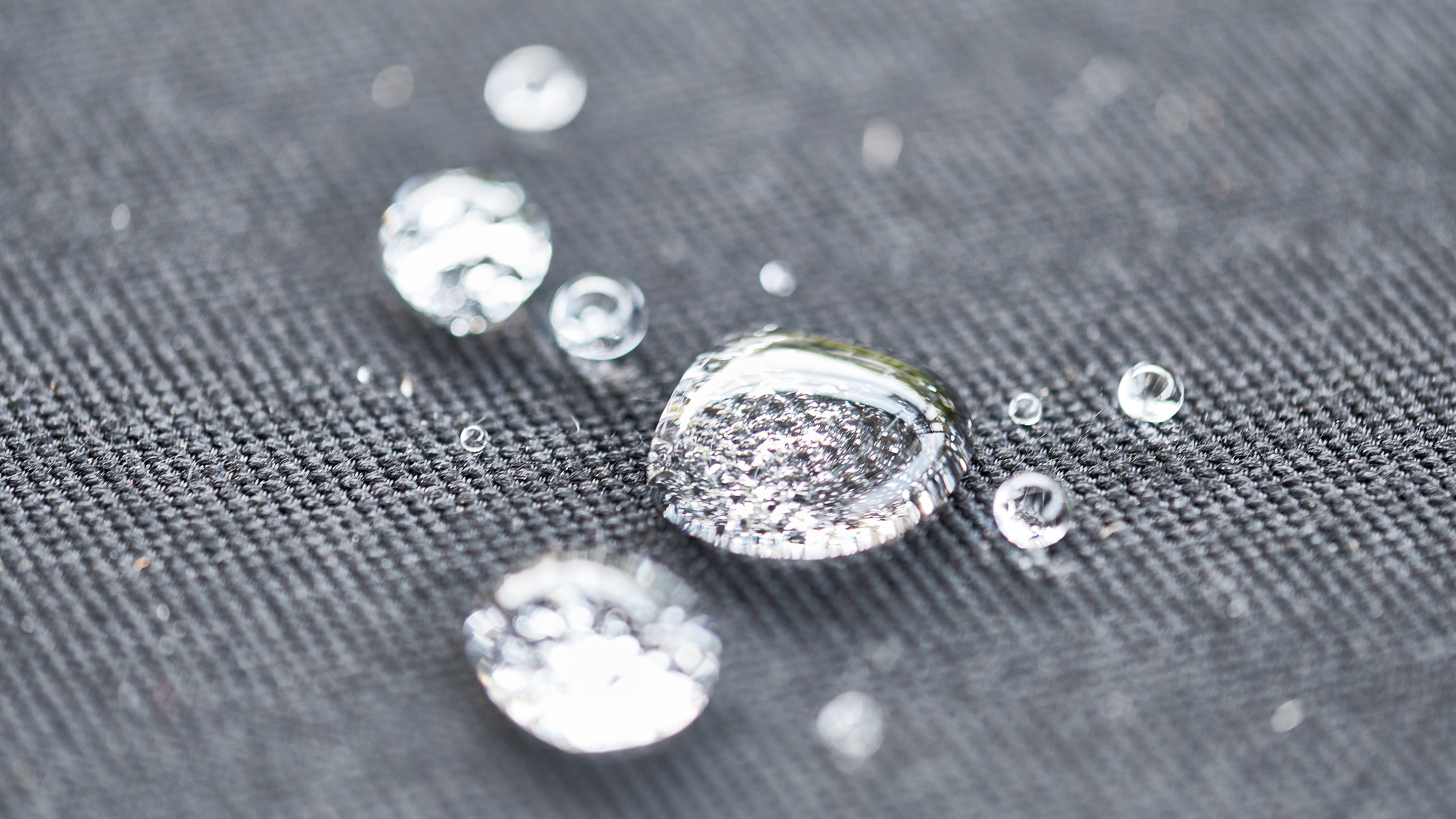 Low surface energy showing water droplets beading on a waterproof textile surface